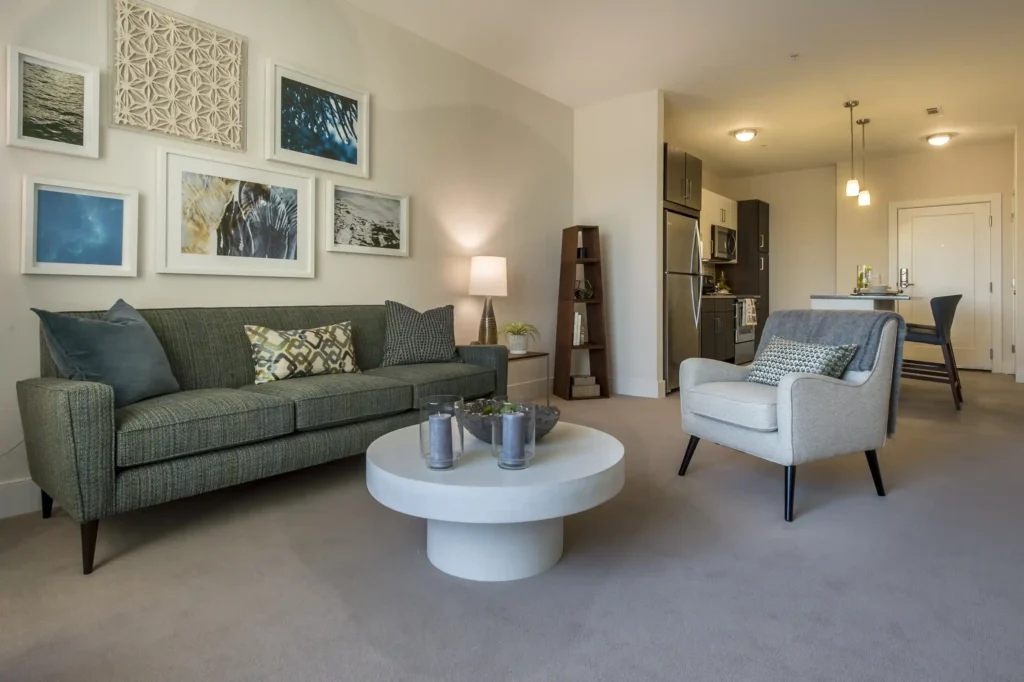 Open living space with sofa and chair, view into the kitchen